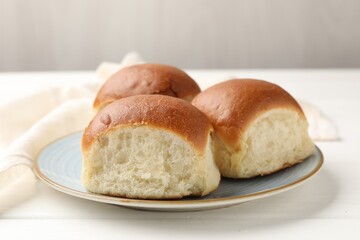 Fresh tasty buns on white wooden table, closeup