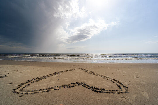 Dunkle Gewitterwolken &uuml;ber D&uuml;nen und Meer. Herz im Sand