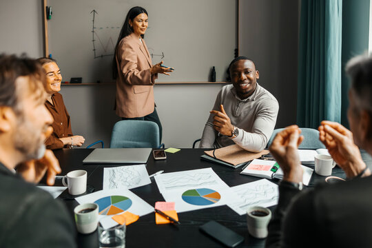 Team of smiling business entrepreneurs sharing ideas in office meeting room