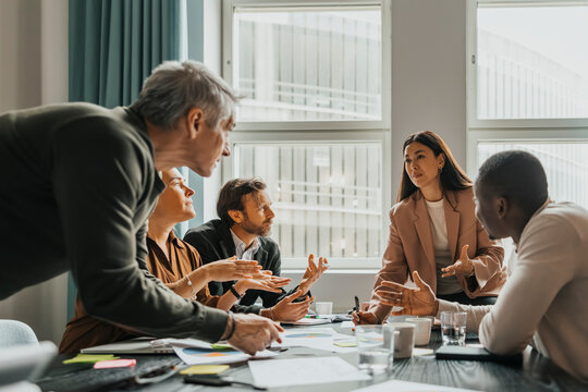 Team of corporate professionals discussing ideas in group meeting at office