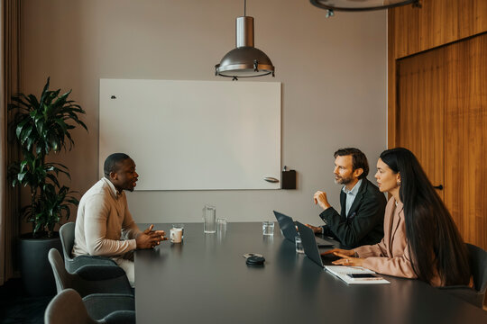 Male candidate talking with managers sitting at table in office meeting room