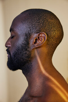 Side view of shirtless man with eyes closed against colored background