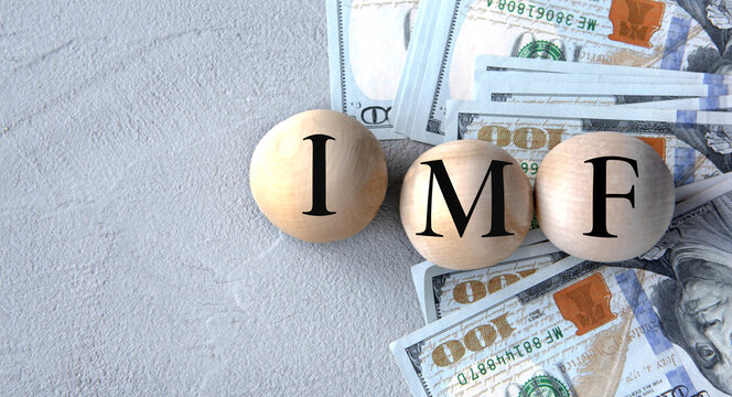 IMF - acronym on wooden balls on the background of banknotes