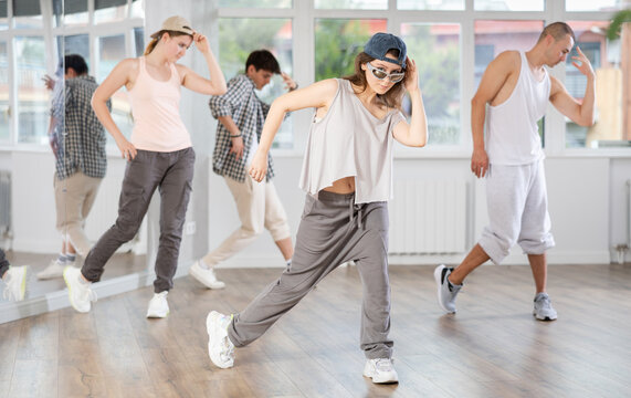 During hip hop dance lesson, girl leads, conducts classes, teaches students to correctly perform elements and sequence of movements and moonwalk