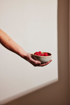 Hand of woman holding strawberry bowl
