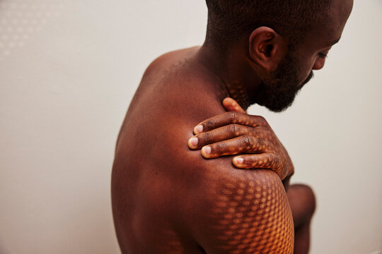High angle view of shirtless man pressing his stiff shoulder