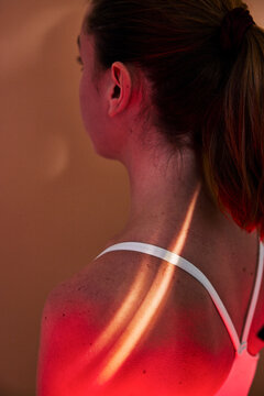 High angle view of sunlight ray shining on woman's shoulder wearing sports bra
