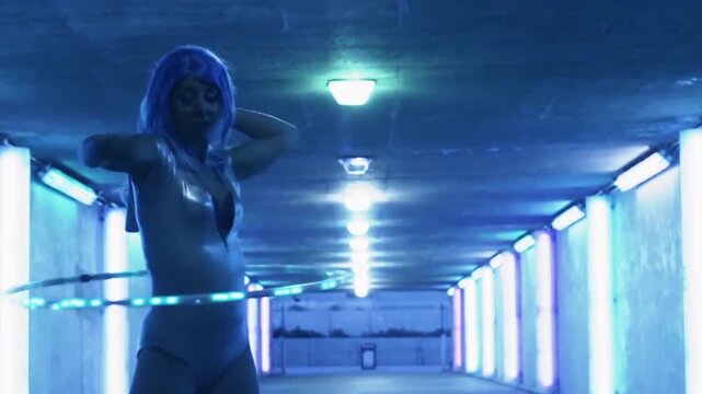 A regular footage of a hula hoop performer woman in an underground