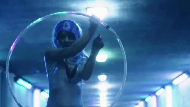 A regular footage of a hula hoop performer woman in an underground