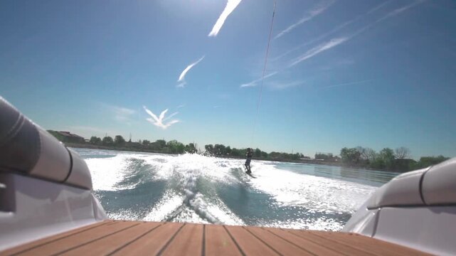 A slow-motion view of a person water skiing with a background of trees growing on a coast