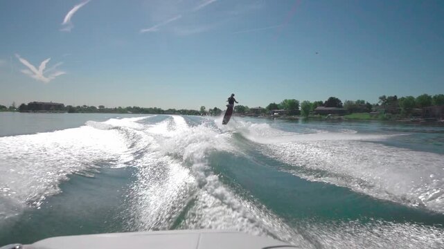 A slow-motion view of a person water skiing with a background of trees growing on a coast