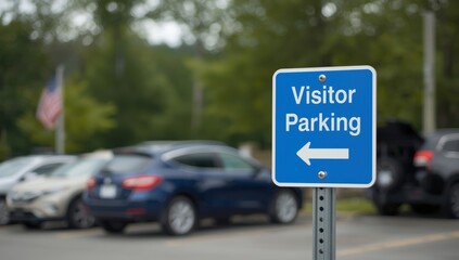 Blue metal sign for visitor parking on a post in a blurred parking lot with trees