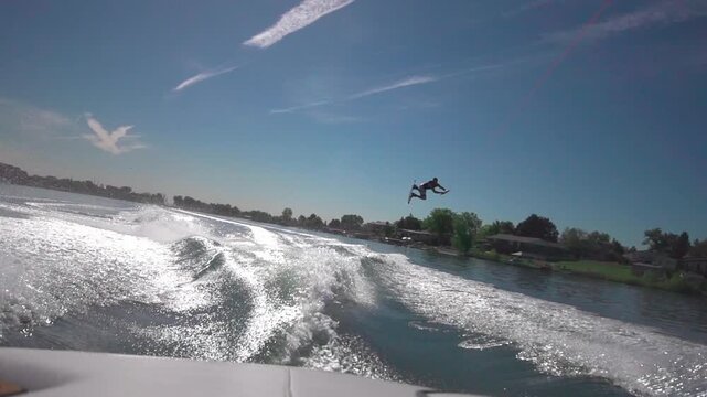 A slow-motion view of a person water skiing with a background of trees growing on a coast