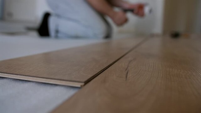 Close up of laminate floor panels being installed in a room. Home renovation process with focus on wooden boards and interior improvement.