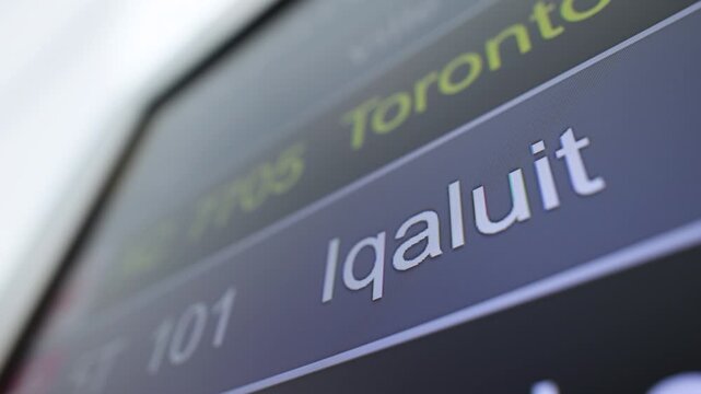 Flight listing board at an airport showing iqaluit delayed and cancelled flights in Canada