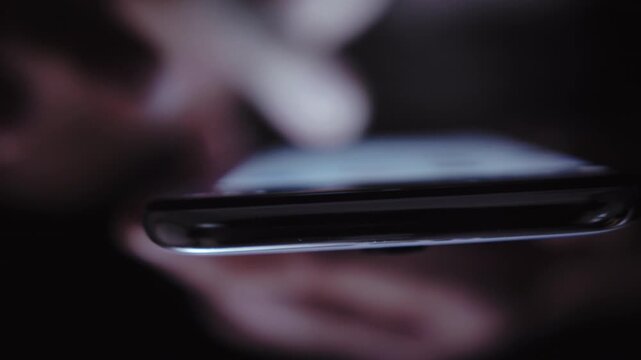 Late-Night News Exploration: Man Indoors Engrossed in Web Browsing on His Smartphone