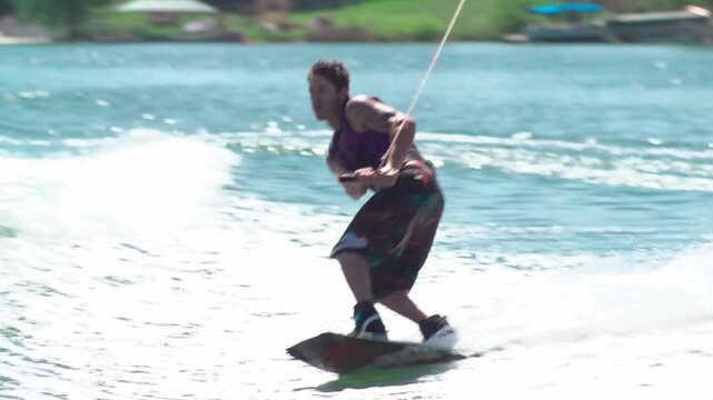 A slow-motion view of a person water skiing with a background of trees growing on a coast