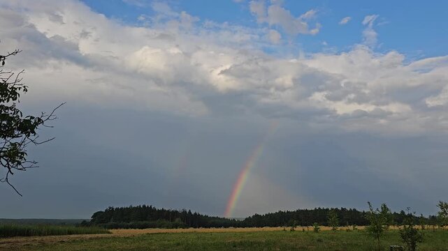 Beautiful rainbow by Icelandic plains descending from cloudscape to ground, from moving car driving by