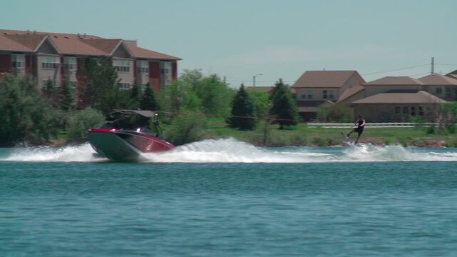 A slow-motion view of a person water skiing with a background of trees growing on a coast