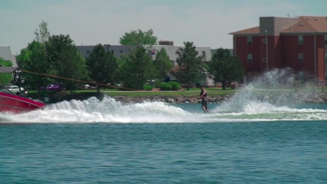A slow-motion view of a person water skiing with a background of trees growing on a coast