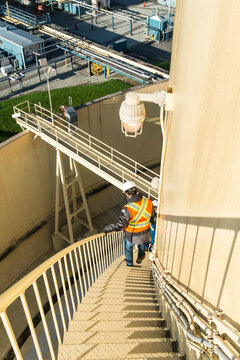 Canada, BC, Delta.  Worker descends steel staircase on the exterior of LNG storage tank.  Liquid Natural Gas