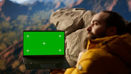 Adventure seeker stands at a mountain peak next to isolated chroma key, looking out at the scenic view that stretches endlessly before him. Fresh air and breathtaking landscape. Camera B. © DC Studio