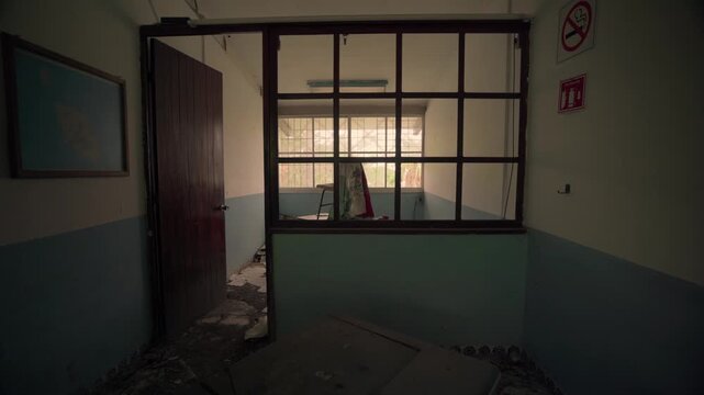 Dolly out movement revealing a deteriorated classroom with a Mexican flag over a desk in a ruined interior. Symbolizes insecurity in Mexico, narco violence, and national abandonment.