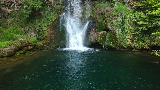 Lisine Waterfall also known as Veliki Buk cascading down rocky cliff into emerald pool in eastern Serbia. Powerful freshwater flow surrounded by lush green vegetation in natural canyon landscape
