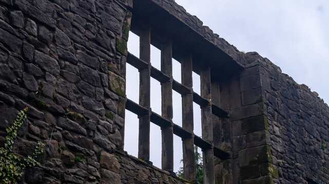 Whalley Abbey ancient, old, ruins. Stone masonry and preserved window opening with stone lintels against a cloudy sky