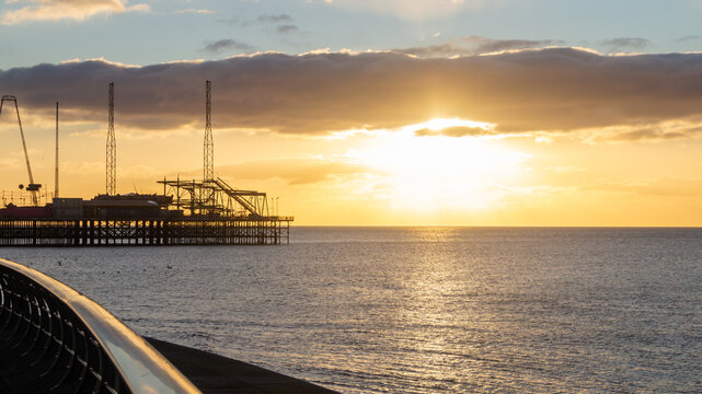 Picturesque sunset over the sea against the backdrop of the pier. Evening sunlight over the sea