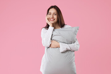 Obraz premium Beautiful woman in stylish pajamas with pillow on pink background