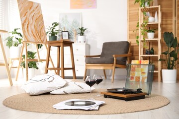 Romantic date. Glasses of wine, record player and vinyl disks on floor indoors