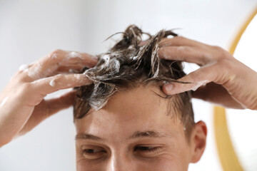 Naklejka premium Man washing his hair with shampoo in bathroom, closeup