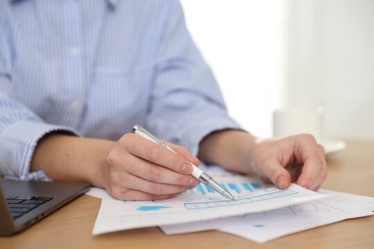 Secretary with pen doing paperwork at table in office, closeup