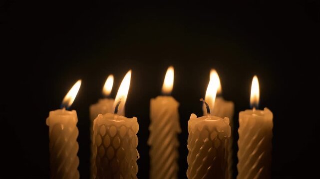 Five lit candles on dark background.