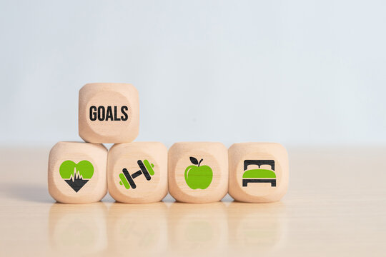 Wooden cubes stacked with goals text and wellness icons. Symbol of personal development, fitness training, healthy eating, rest balance and lifestyle objective planning.