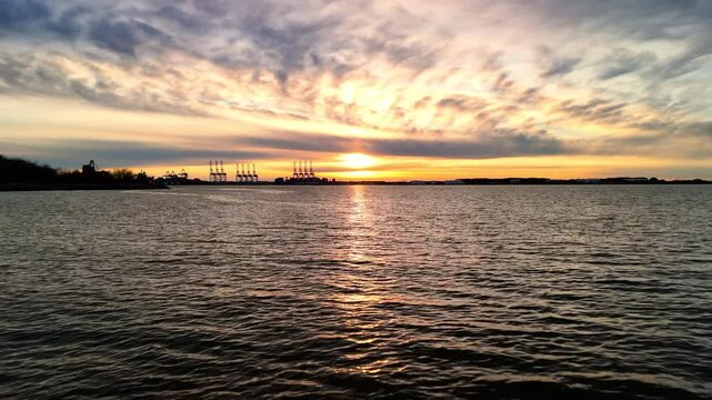 Dramatic sunset over the Elizabeth River industrial harbor and Norfolk Virginia skyline at golden hour