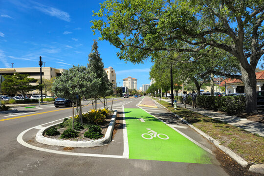 Designated green bike lane on busy Sarasota street in Florida, bordered by traffic and promoting sustainable urban transportation