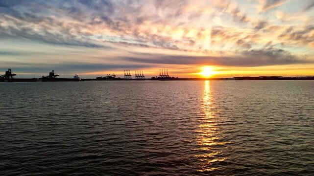 Dramatic sunset over the Elizabeth River industrial harbor and Norfolk Virginia skyline at golden hour