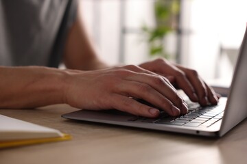 Fototapeta premium Man working on laptop at wooden desk, closeup