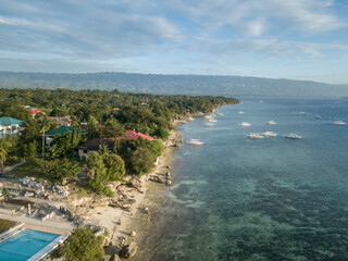 Fototapeta premium Aerial sunset view of Moalboal coastline with turquoise waters and coral reef in the Philippines