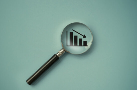 magnifier over the decreasing or descending graph. Economic crisis and financial recession