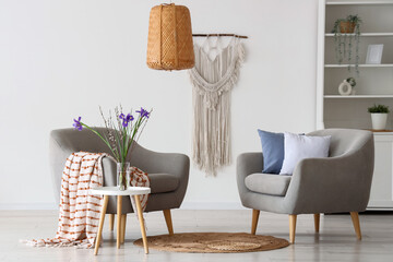 Interior of light living room with armchairs and spring flowers