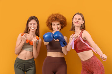 Group of female friends with sports equipment on yellow background