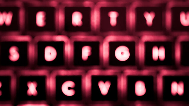 Abstract out of focus view of backlit laptop keyboard in red tone