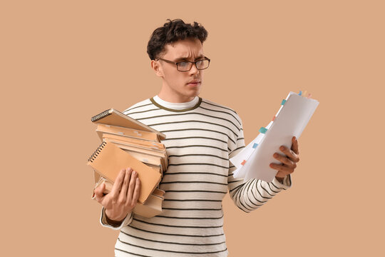 Male screenwriter with scenario and books on beige background