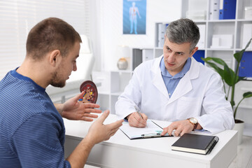 Obraz premium Man having appointment with urologist at white desk in clinic