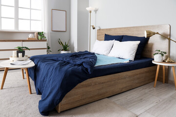 Interior of light room with electric heating pad on bed, tables and plants © Pixel-Shot