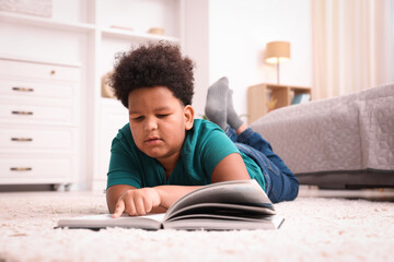 Fototapeta premium Boy reading book on floor at home