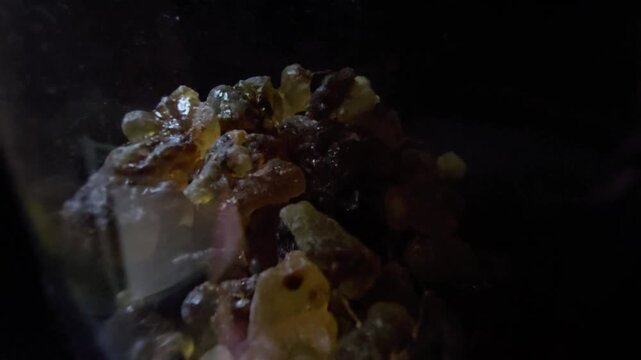Macro video of Frankincense resin over a black background. Sharp focus on textures and amber colors, perfect for organic and wellness visuals.